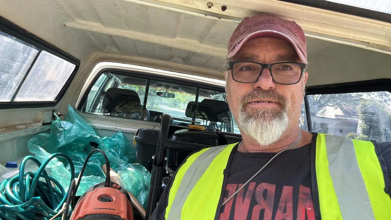 Tony Bekker wearing a high-visibility vest beside equipment in the company vehicle